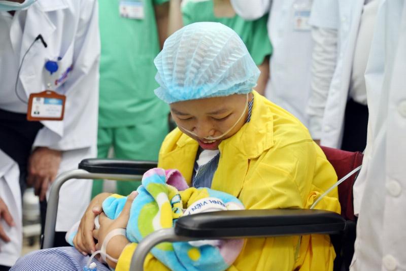 Hình ảnh một người mẹ đang ôm con và mỉm cười, thể hiện niềm hạnh phúc và sự kết nối sau sinh